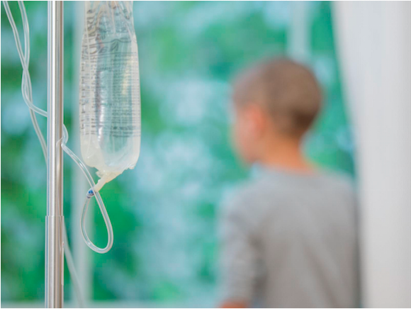 Image of an IV drip with a child in the background.