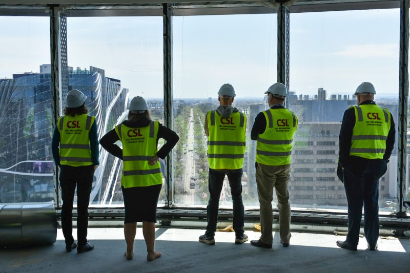 People in CSL hi-vis vests looking out the window over the biomedical precinct