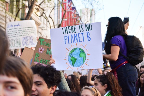 Group of people with one holding a sign saying "There is no planet B" with a drawing of Earth