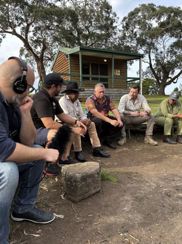 Six people sit around the campfire having a yarn at Budj Bim.