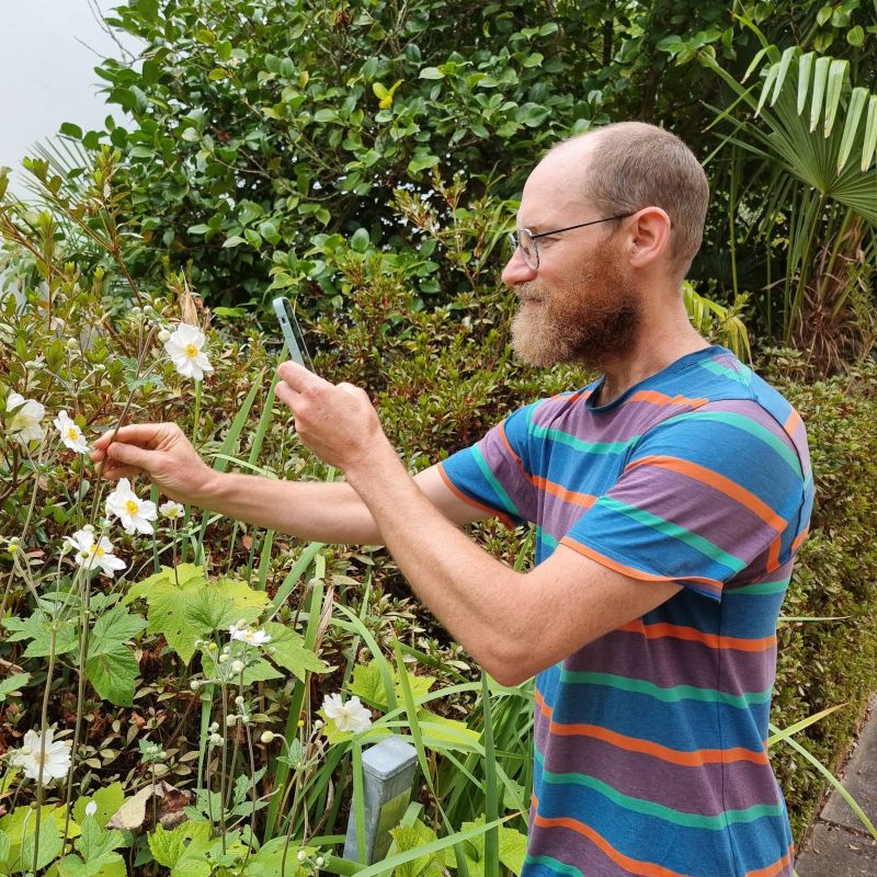 A man with light brown hair and glasses examining plant life at the Creswick campus