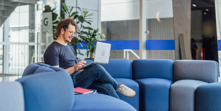 An alum sitting on a couch browsing information on the alumni eJournals subscription.