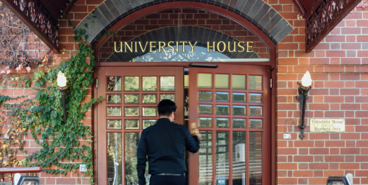 An alum walking into the front entrance of University House.