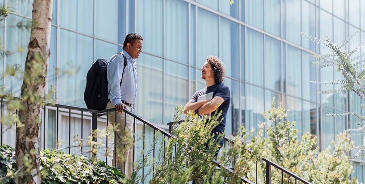 Two alums standing on a staircase discussing potential volunteeriing opportunities.