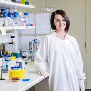 Dr Neville wearing a lab coat in a lab setting. 
                                class=