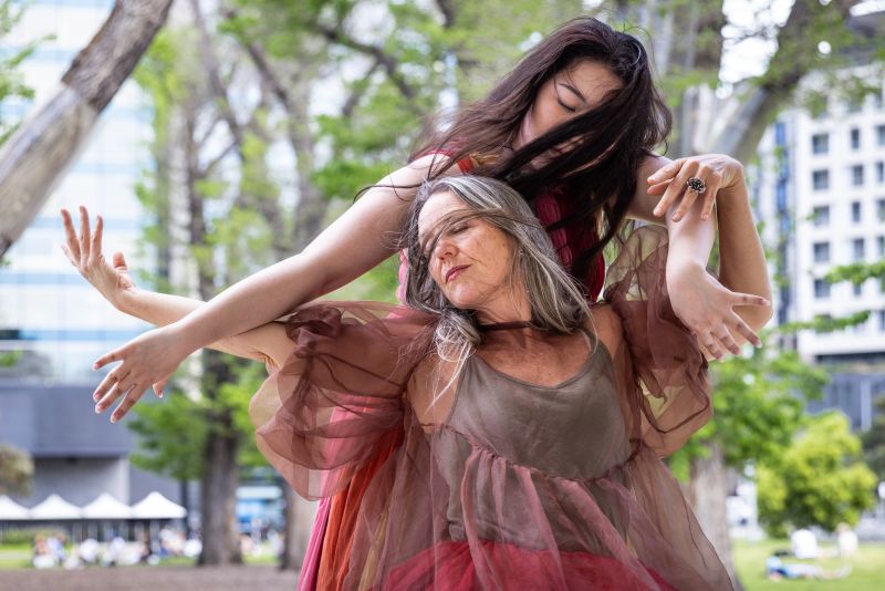 Two dancers performing Plant Table outdoors wearing earth coloured costumes