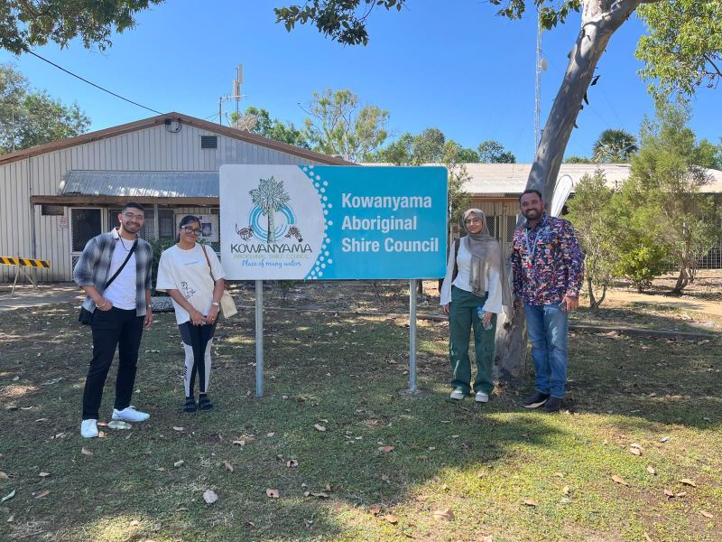 People standing beside a sign for the Kowanyama Aboriginal Shire Council