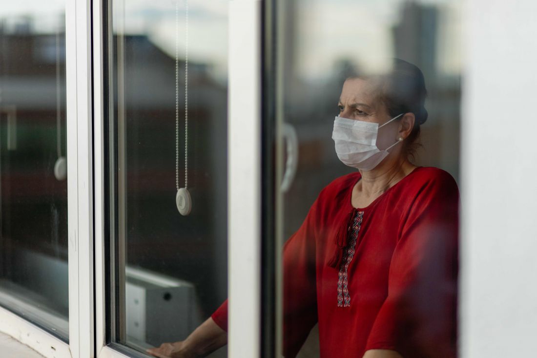 Woman wearing face mask looking out her window