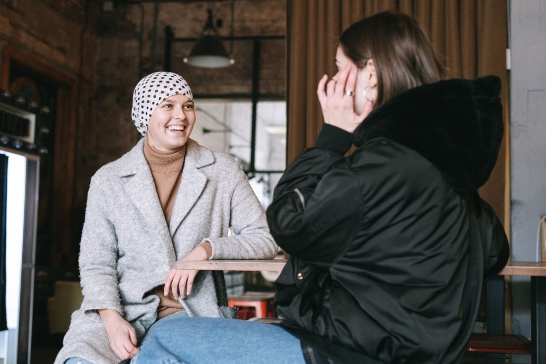 Person with brain cancer talking to someone in a cafe setting