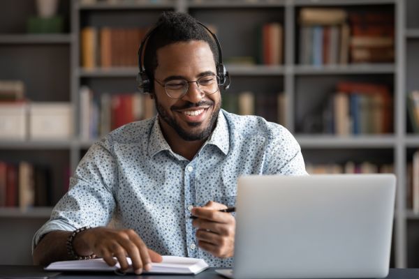 A man sits in their study with a laptop talking to someone in an online chat