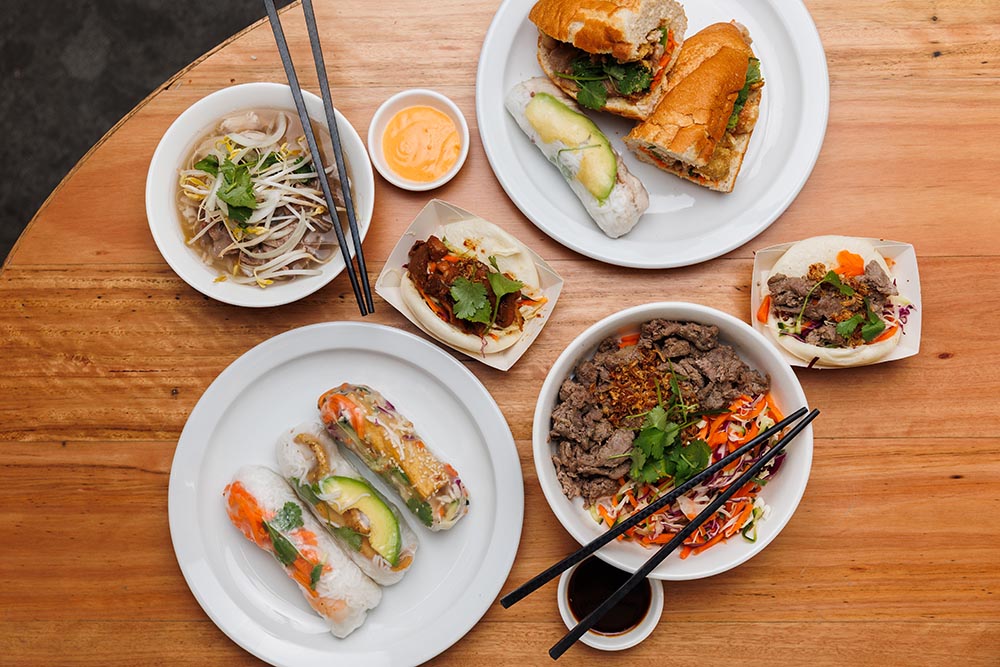 Looking down at a table with a selection of Vietnamese dishes including rice paper rolls
