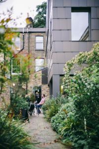 People sitting and conversing in a lush garden alley beside a modern building.
