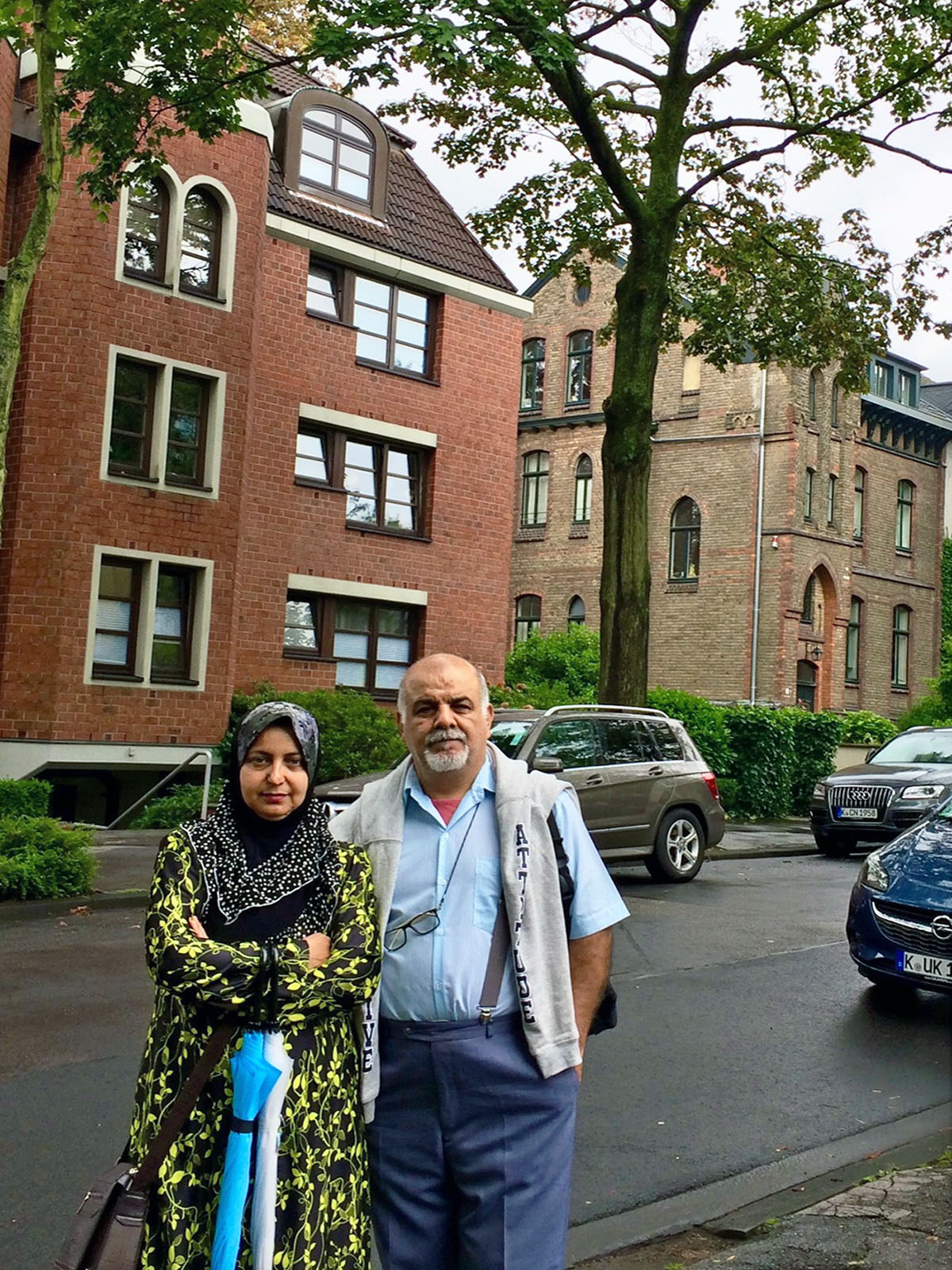 A man and a woman standing close together on a tree lined street