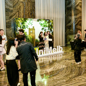 Alumni mingling at a Beijing Alumni Association event with a Parkville-inspired photo opportunity in the background.
                                class=
