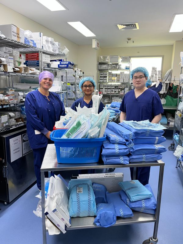 Three nurses/students wearing medical hair nets standing in a laboratory