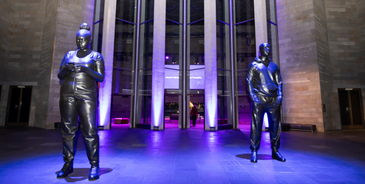 Statues and purple lighting at the entrance of the NGV.