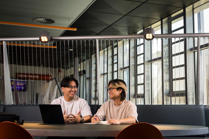 Ken (left) and Calvin (right) smiling at each other while studying outside Union Theatre.