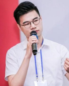A photo of Chunfeng Liao speaking into a microphone at a Guangdong Alumni Association event.