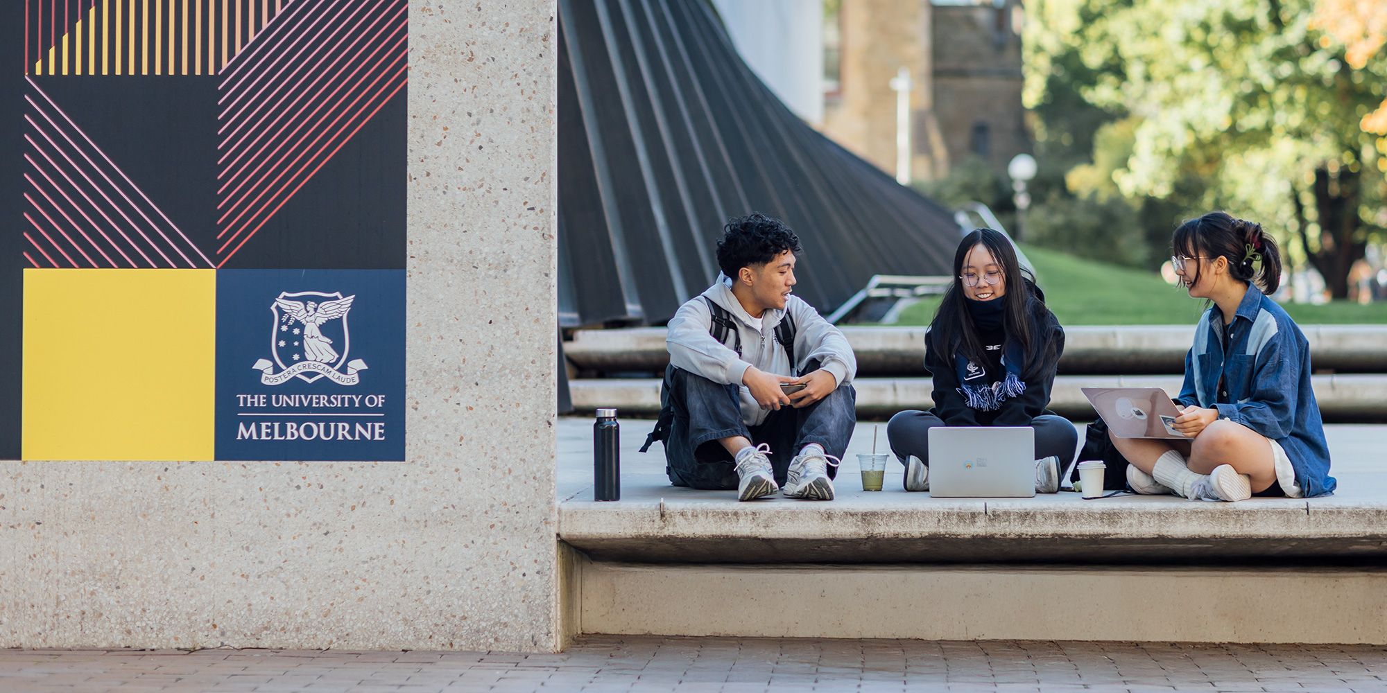 3 students sitting in University Square with their laptops
