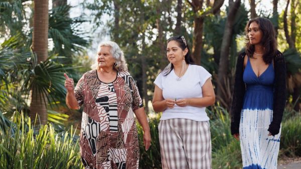 three women talking while walking in a garden