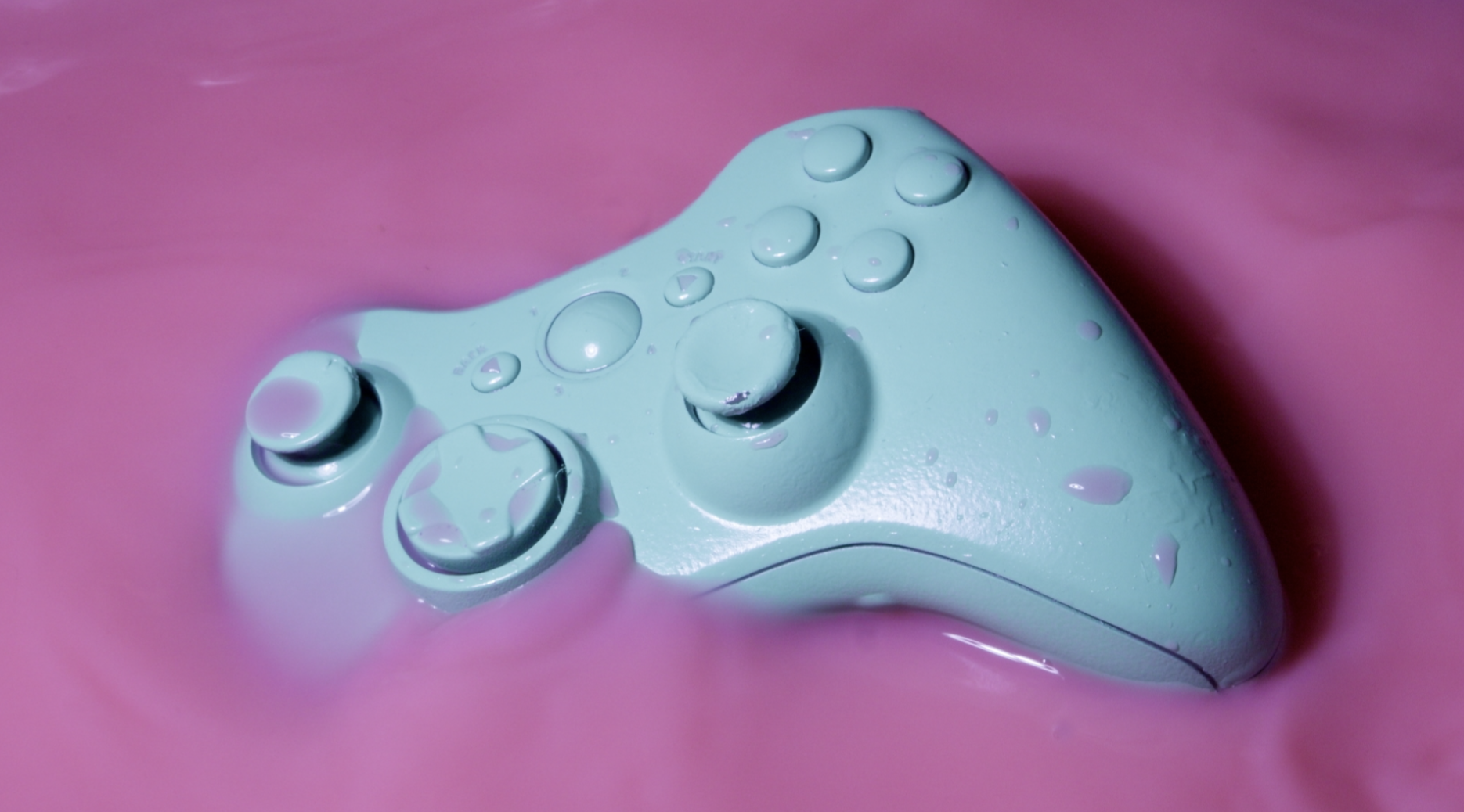 Blue game controller disappearing into pink background