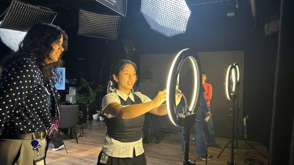 Two women in a studio learning to operate a ring light.