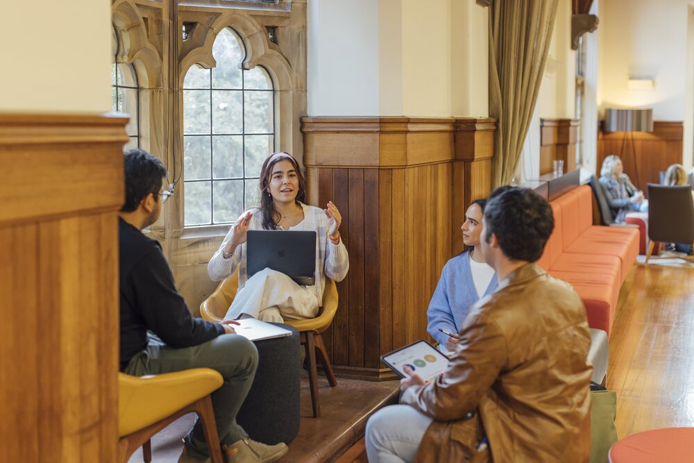 A diverse group of people engaged in conversation while seated in a well-lit room.
