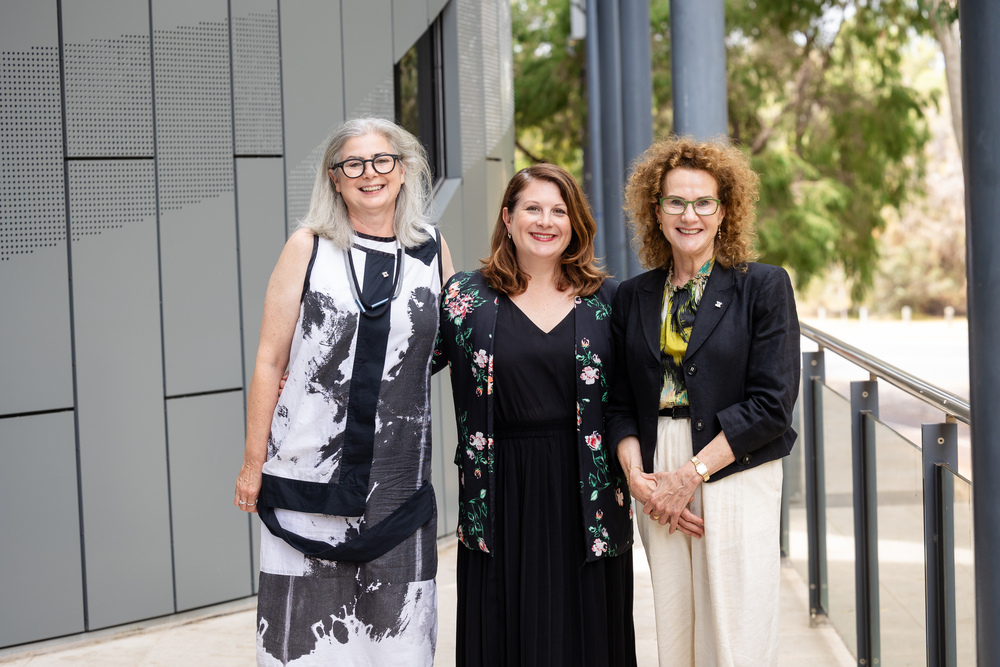 Three individuals smiling and posing for a photo. 
