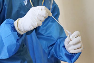 Image of health worker wearing protective gear and holding a testing swab.