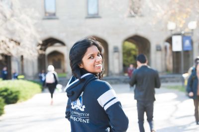 Woman wearing a University of Melbourne hoodie looks at camera