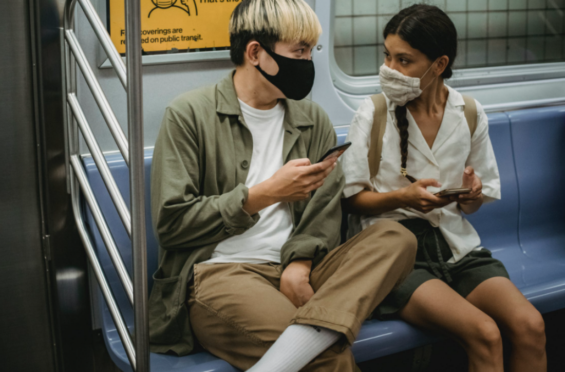 Young people wearing masks on a train look at their phones
