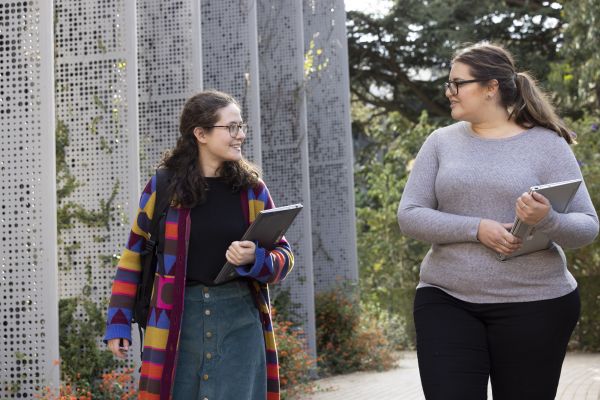 Honours student Rebekka walking through campuss talking to a classmate.