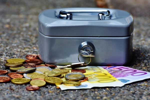 A grey metal locked box with coins and cash scattered around it 