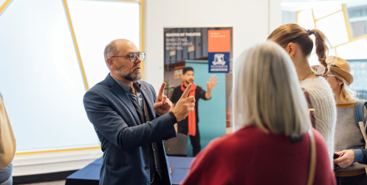 An older alumni volunteer conversing with a student at a University event.