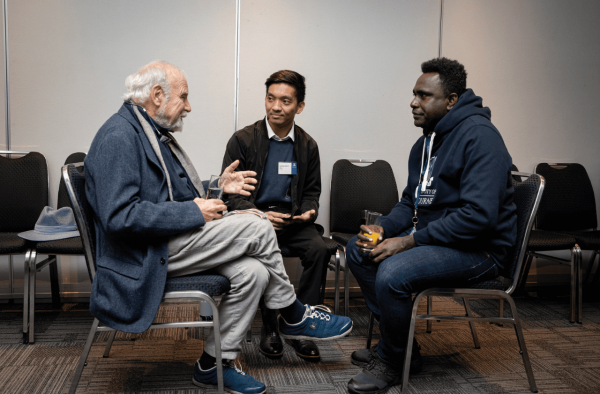 An alumni volunteer talking with two students at a Welcome to Melbourne launch event.