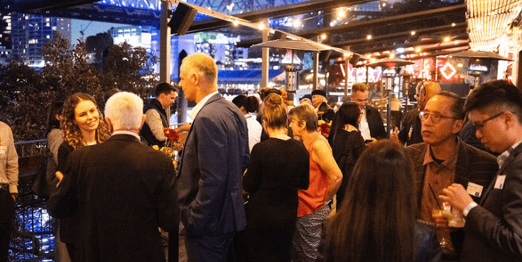 A large group of alumni mingling at an outdoor bar.