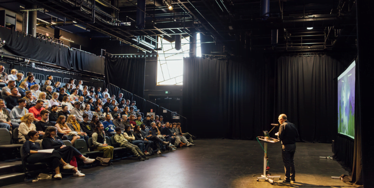 A professor delivering a lecture to a large group on campus.