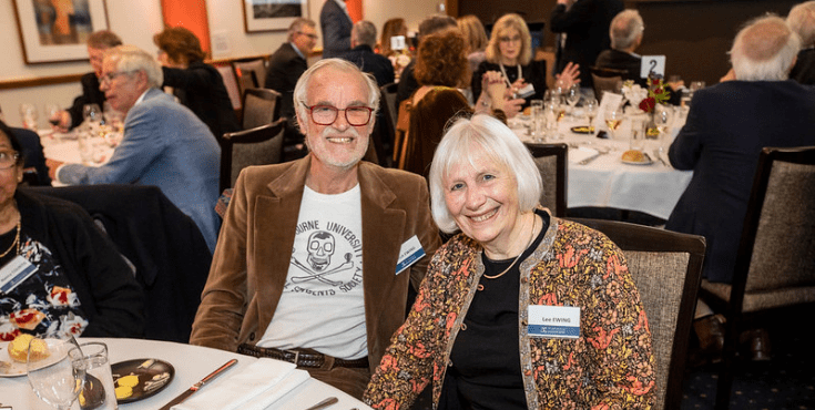 An group of older alumni smiling and conversing at an alumni reunion.