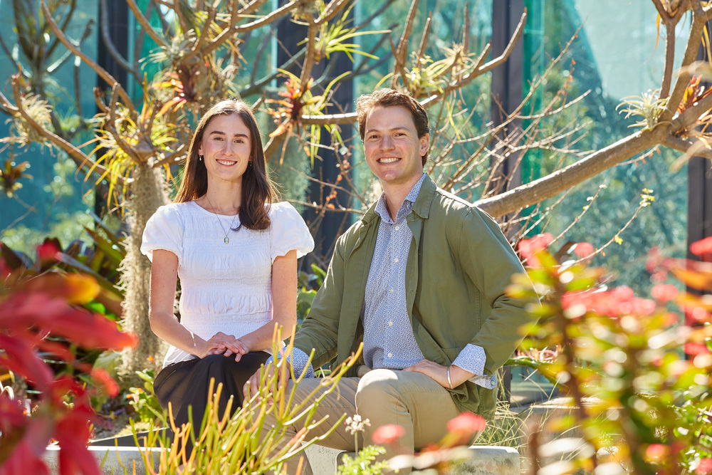 A male and female sitting amongst greenery.