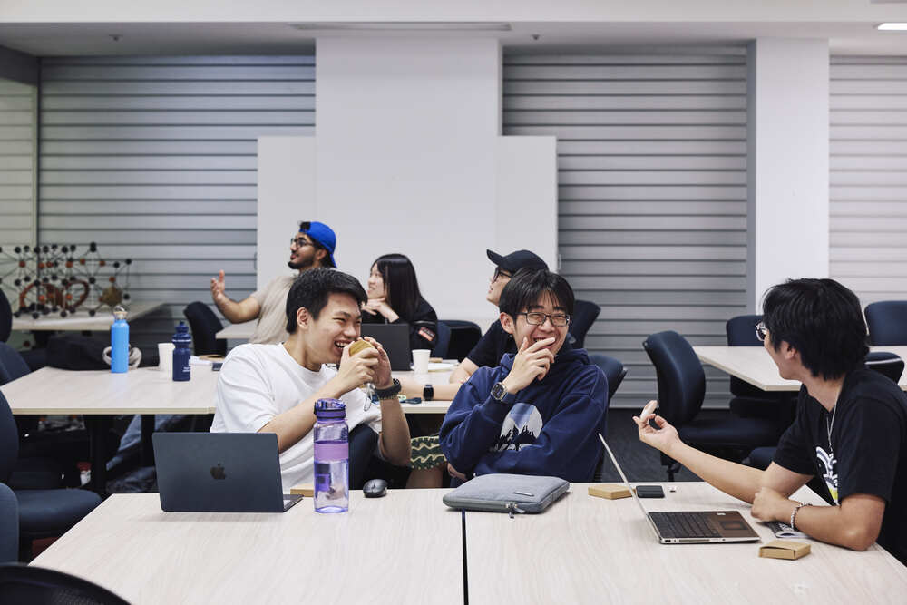 A group of students in discussion in a classroom setting.