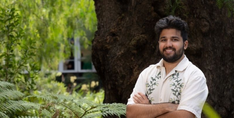 Student standing in front of a tree