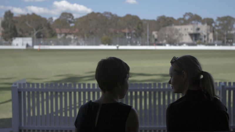 two people sitting by a sports oval