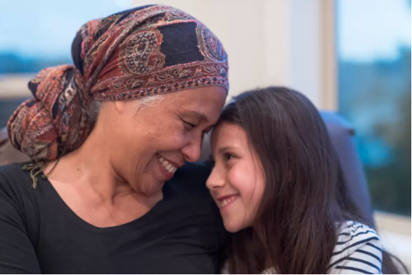 Image of a middle aged lady wearing a headscarf holding a young girl close.