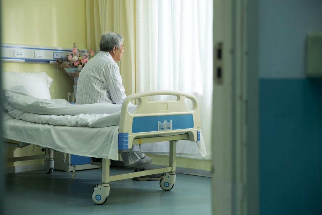 Elderly Chinese man siting on the edge of a bed