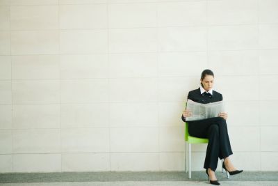 Image of a seated woman reading a newspaper.