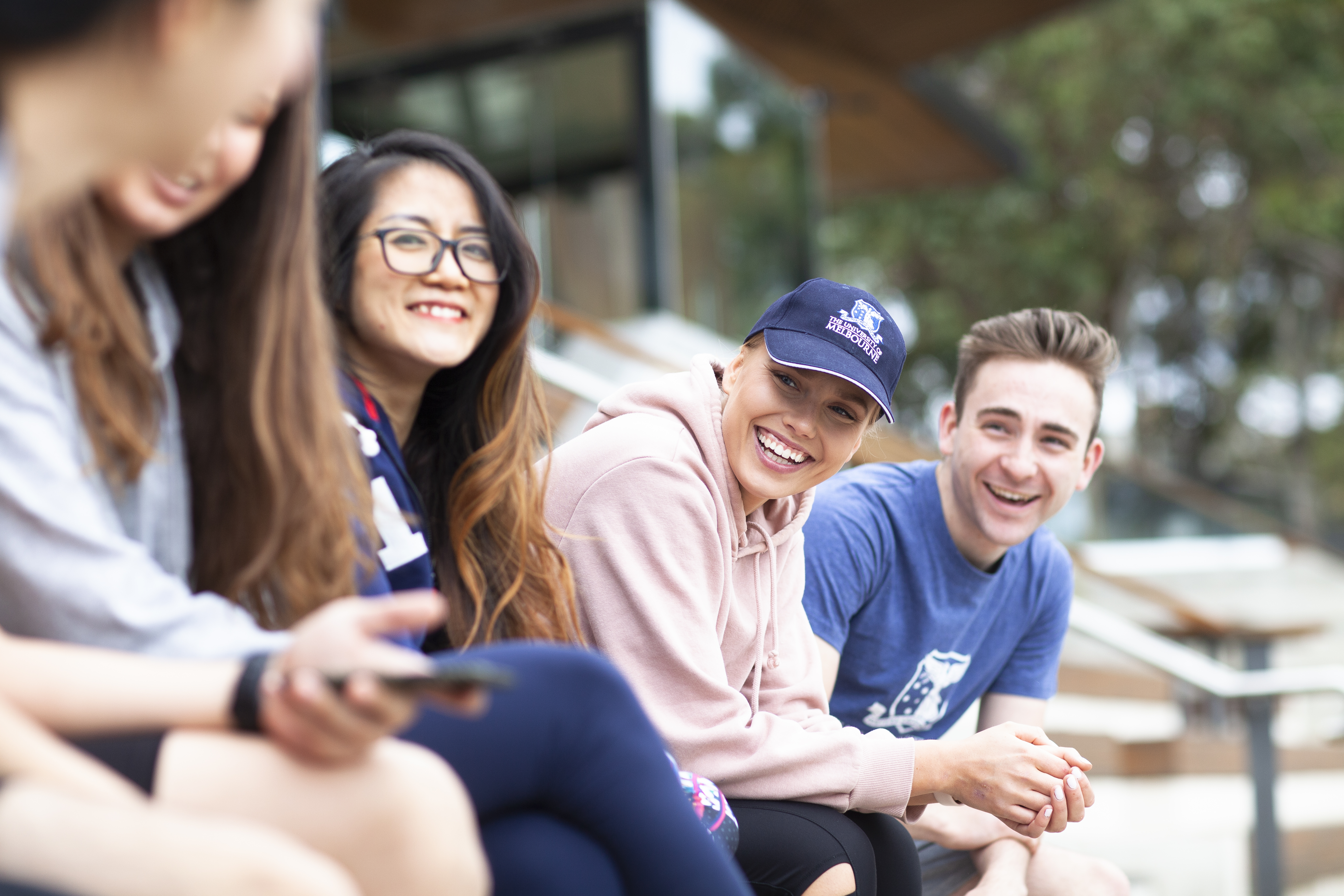 Four students sitting in front of the Ernie Cropley Sports Pavillion