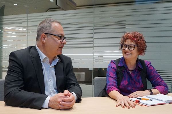 Two people sitting at a desk having a conversation