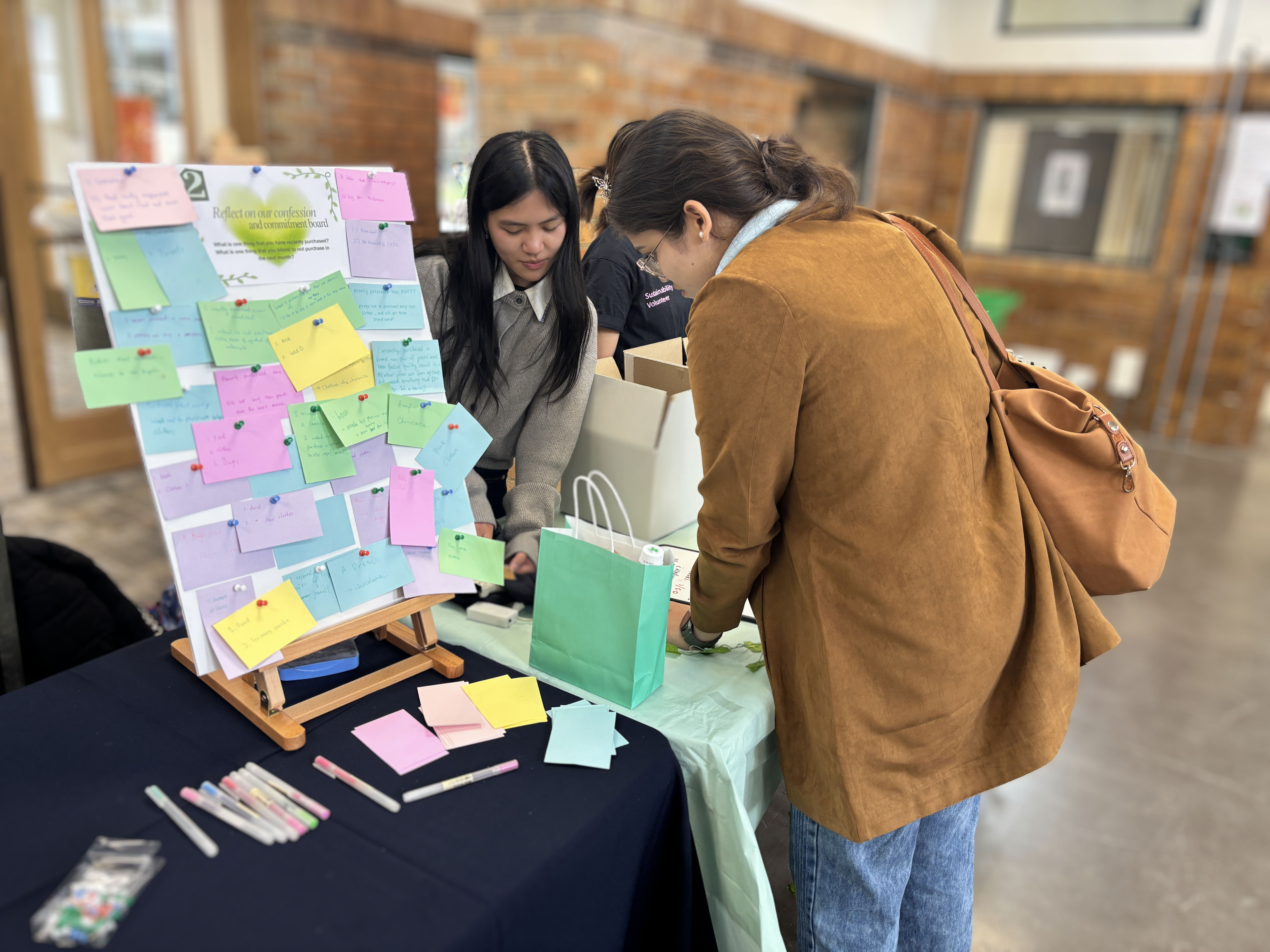 Students writing notes on sticky notes at an indoor engagement table