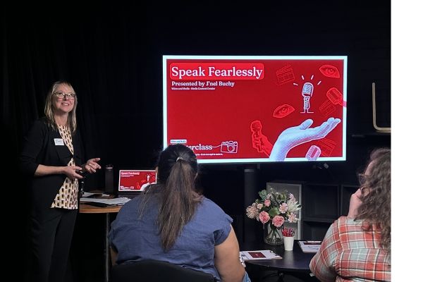 Fearless.jpg A woman presents her Speak Fearlessly slide to a small group in a studio.