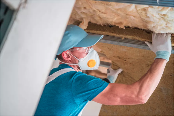 Image of a tradesman inserting insulation at a construction site.